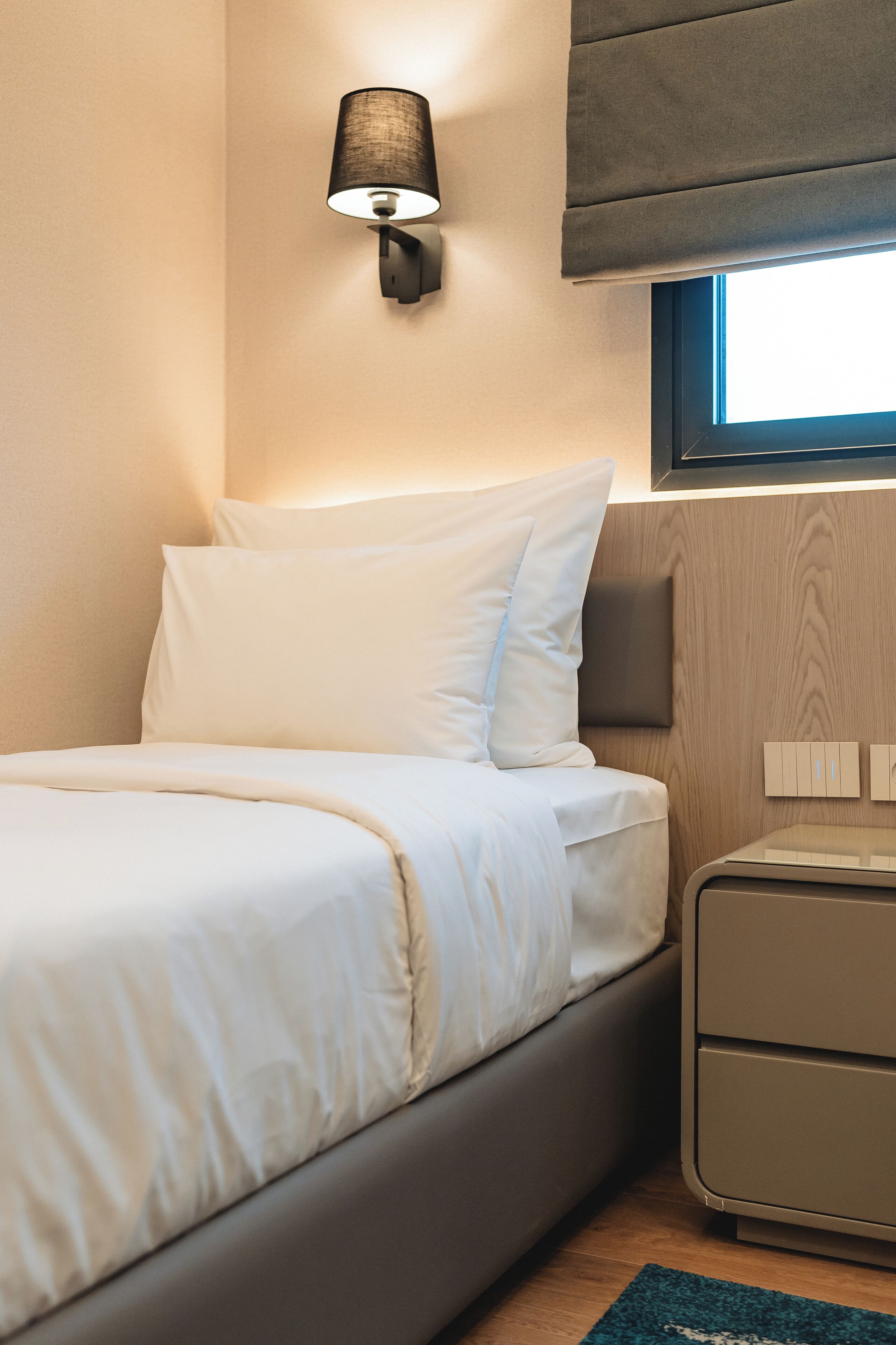 A modern bedroom with a bed, bedside lamp, and a nightstand.