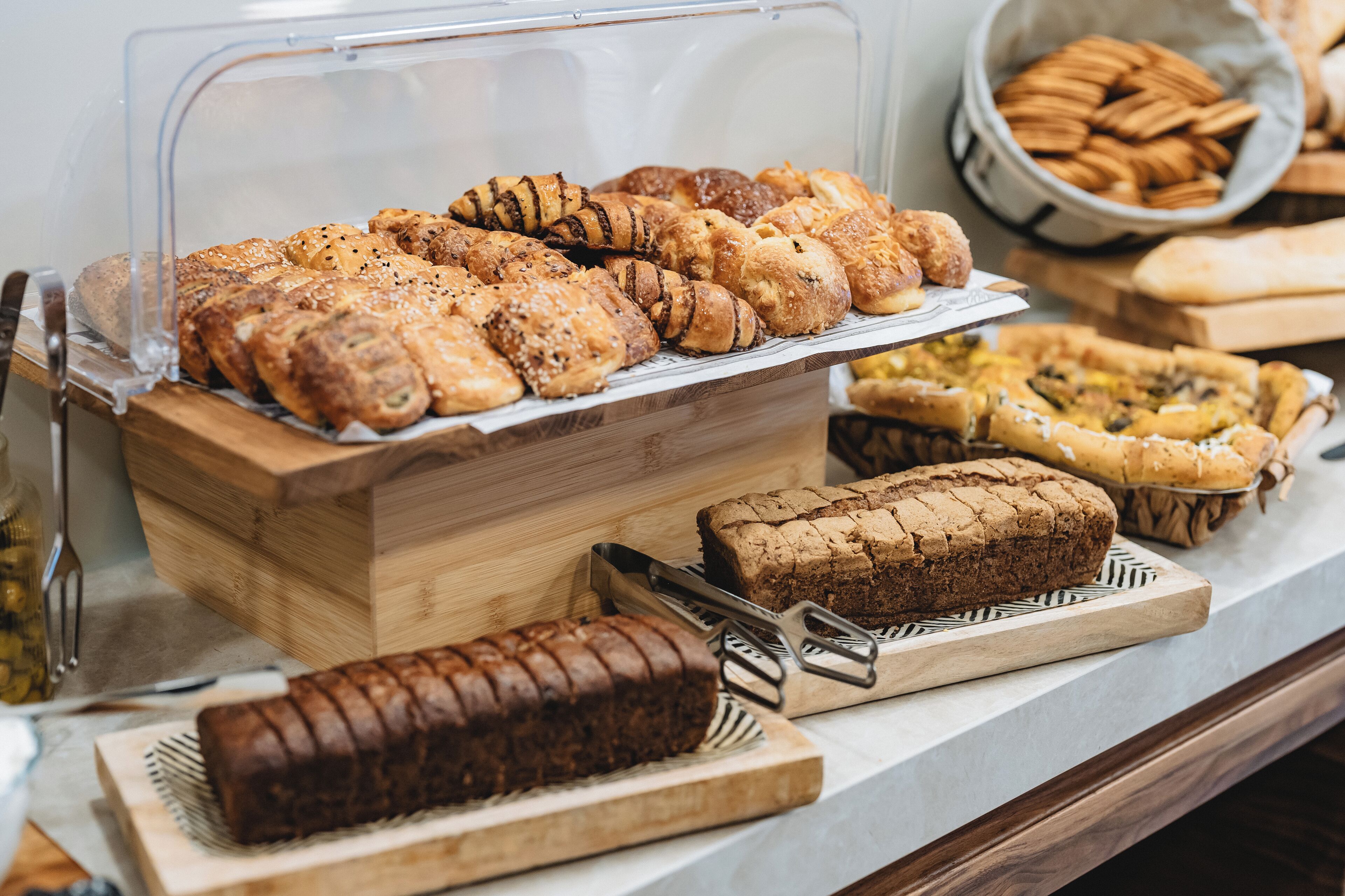A variety of baked goods displayed in a bakery section, including bread, pastries, and cookies.