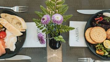 A table set with plates of food, a vase with flowers, and a menu.