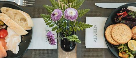 A table set with plates of food, a vase with flowers, and a menu.