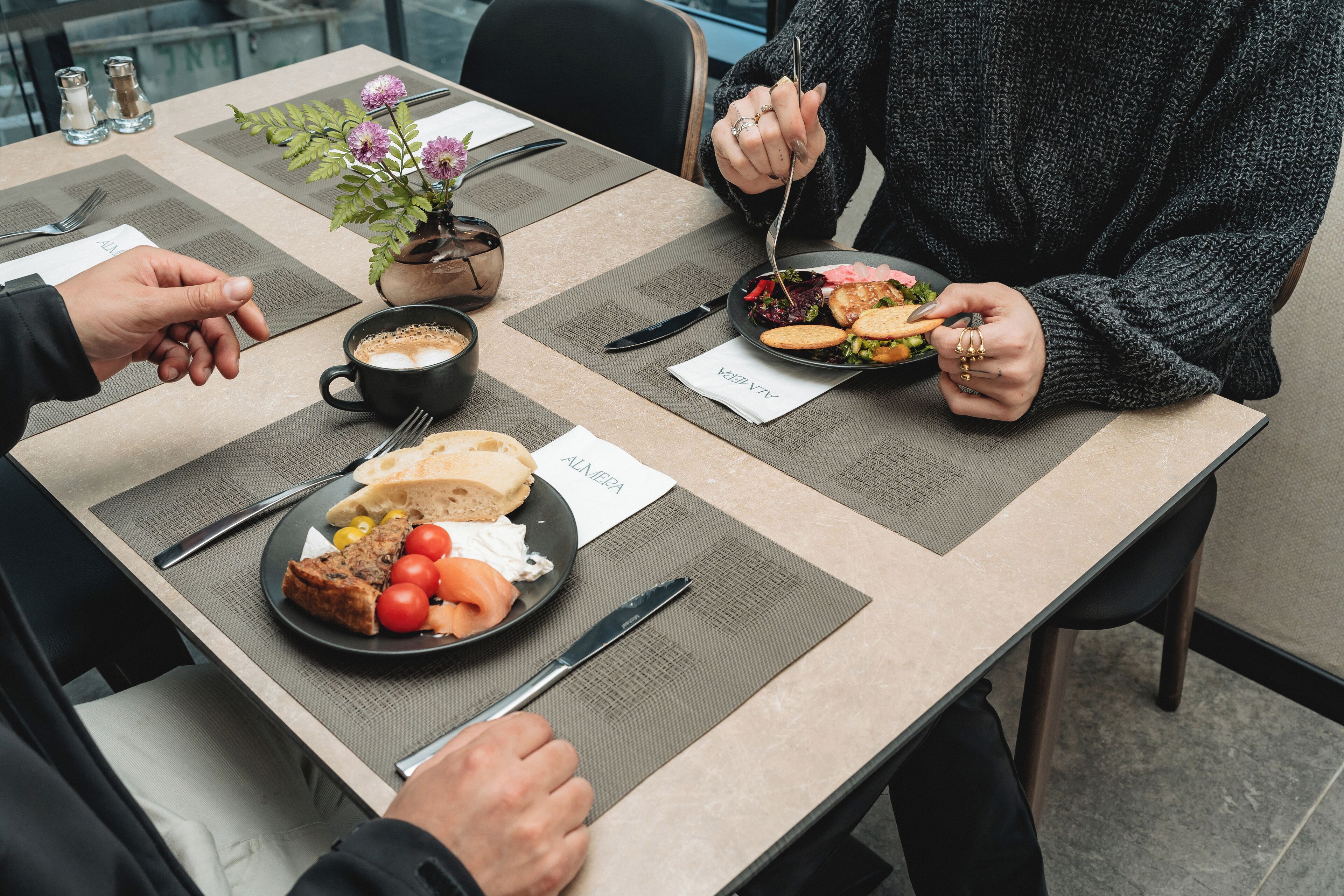 A dining table with a meal, a coffee cup, and a small potted plant.