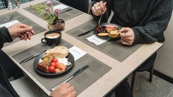 A dining table with a meal, a coffee cup, and a small potted plant.
