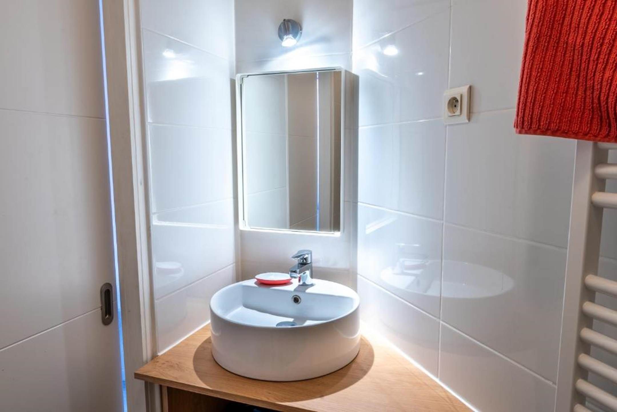 A modern bathroom with a round sink, a mirror, and a towel rack.