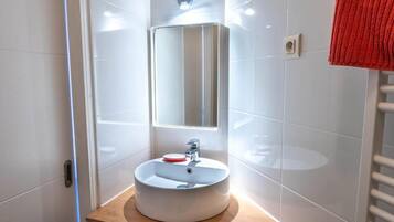 A modern bathroom with a round sink, a mirror, and a towel rack.