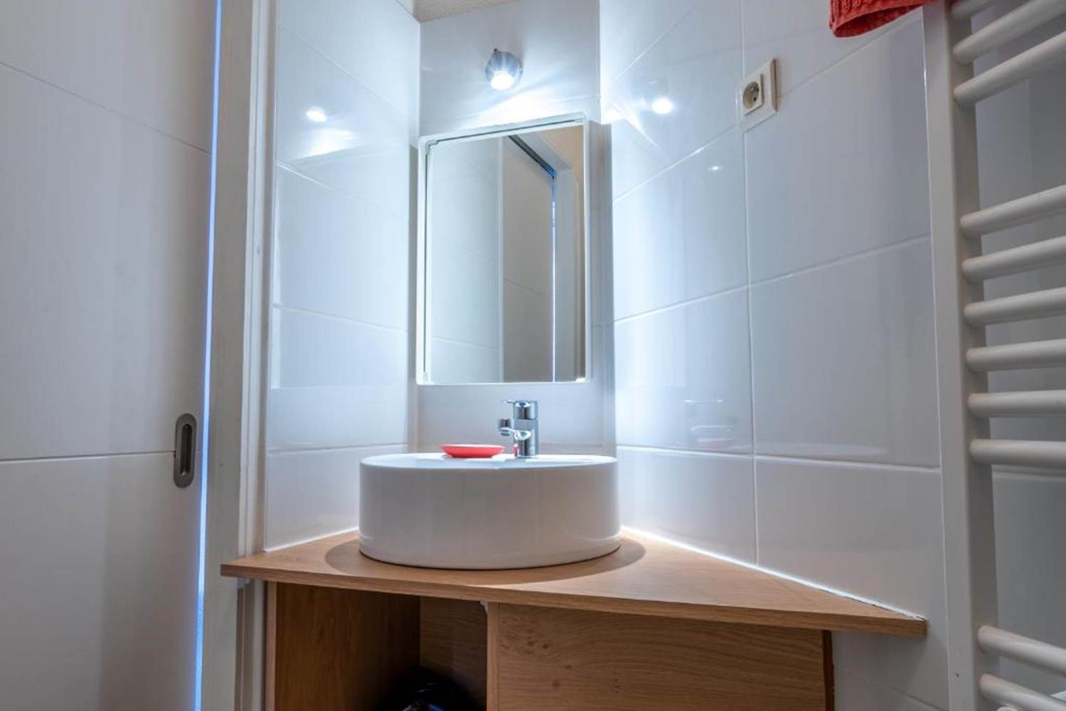 A bathroom with a white sink, a mirror, and a towel rack.
