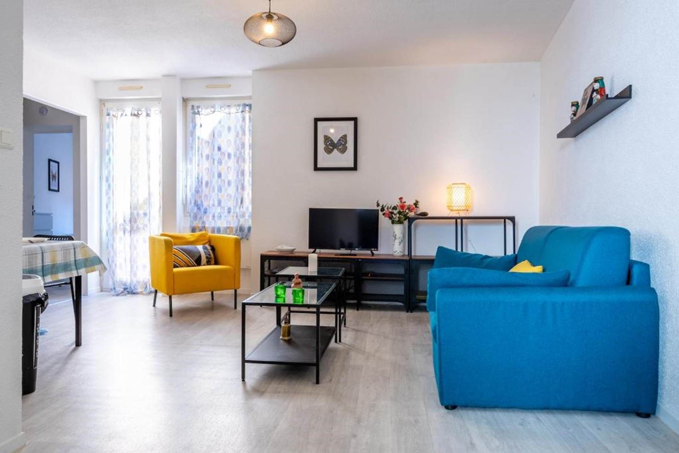A living room with a blue sofa, a yellow armchair, a TV, and a lamp.