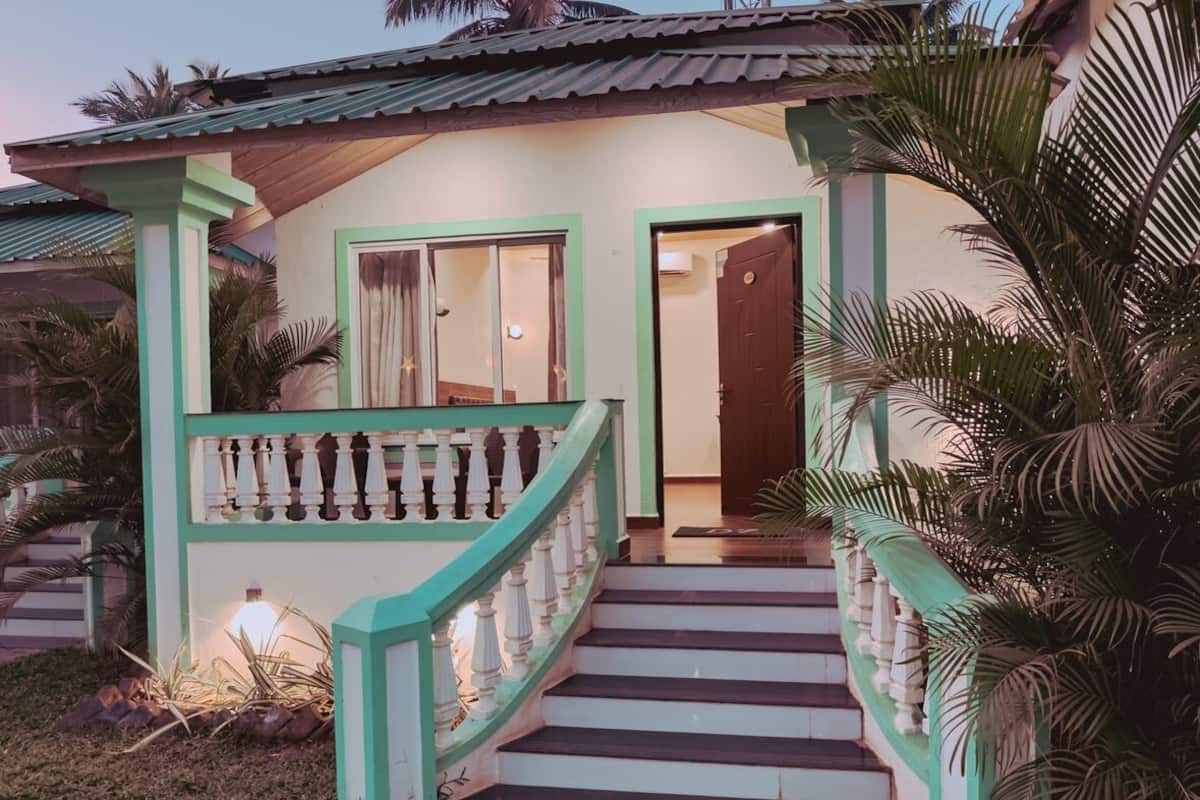 A house with a staircase leading to a door, surrounded by palm trees.