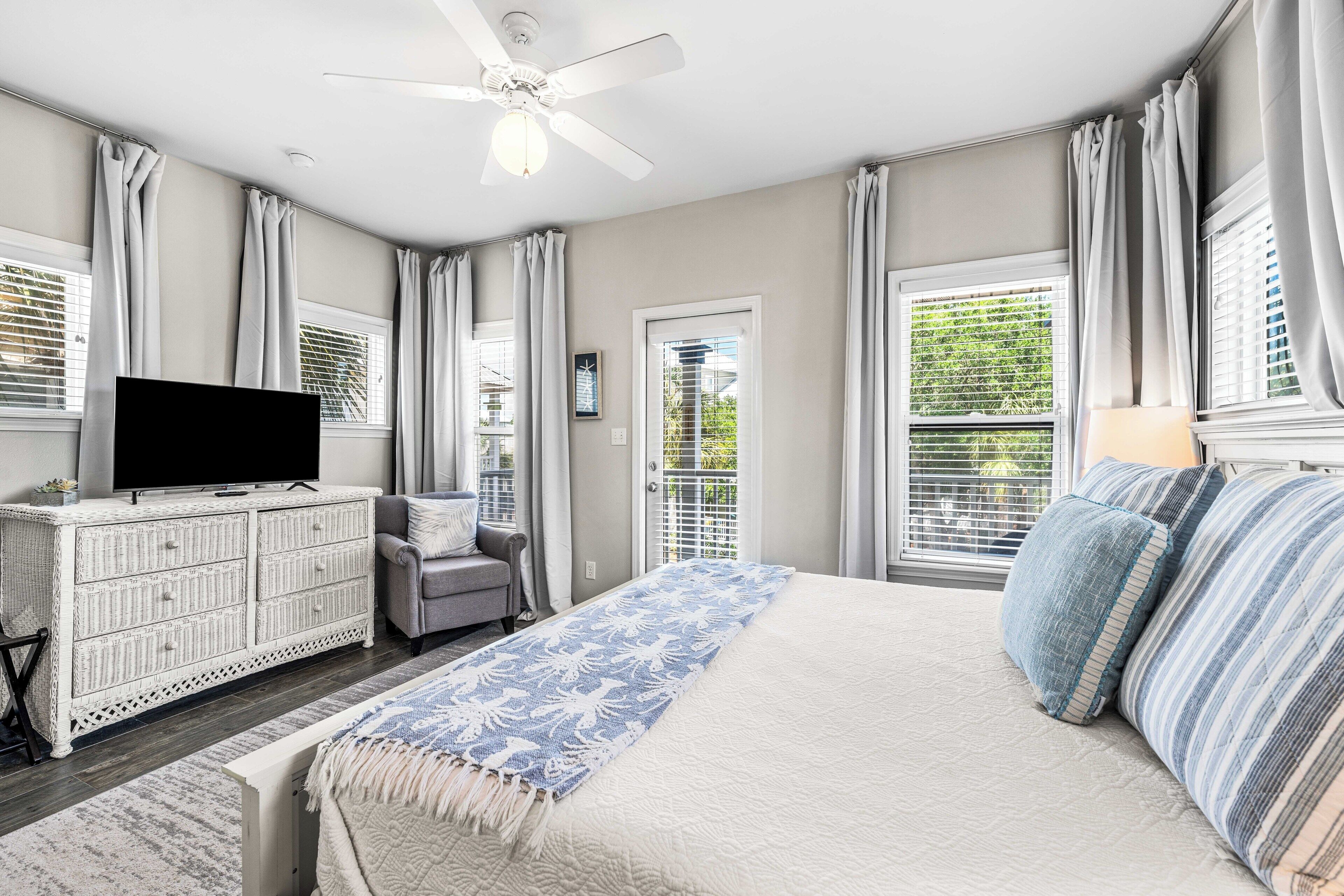 Une chambre à coucher avec un lit, une télévision, une commode, une chaise et une fenêtre avec des stores.