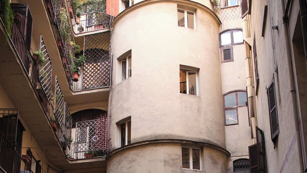 Un patio con un edificio circular, plantas en macetas y una entrada cubierta.