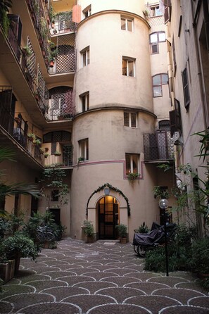 A courtyard with a circular building, potted plants, and a covered entrance. - Bonnavista inn (Rome)