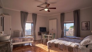 Habitación de hotel con cama, escritorio, silla, televisor y vista de la ciudad.