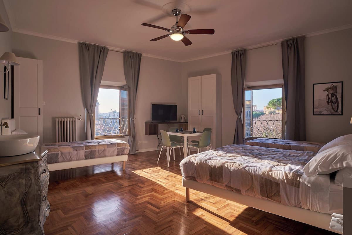 A hotel room with a bed, a desk, a chair, a television, and a view of the city.