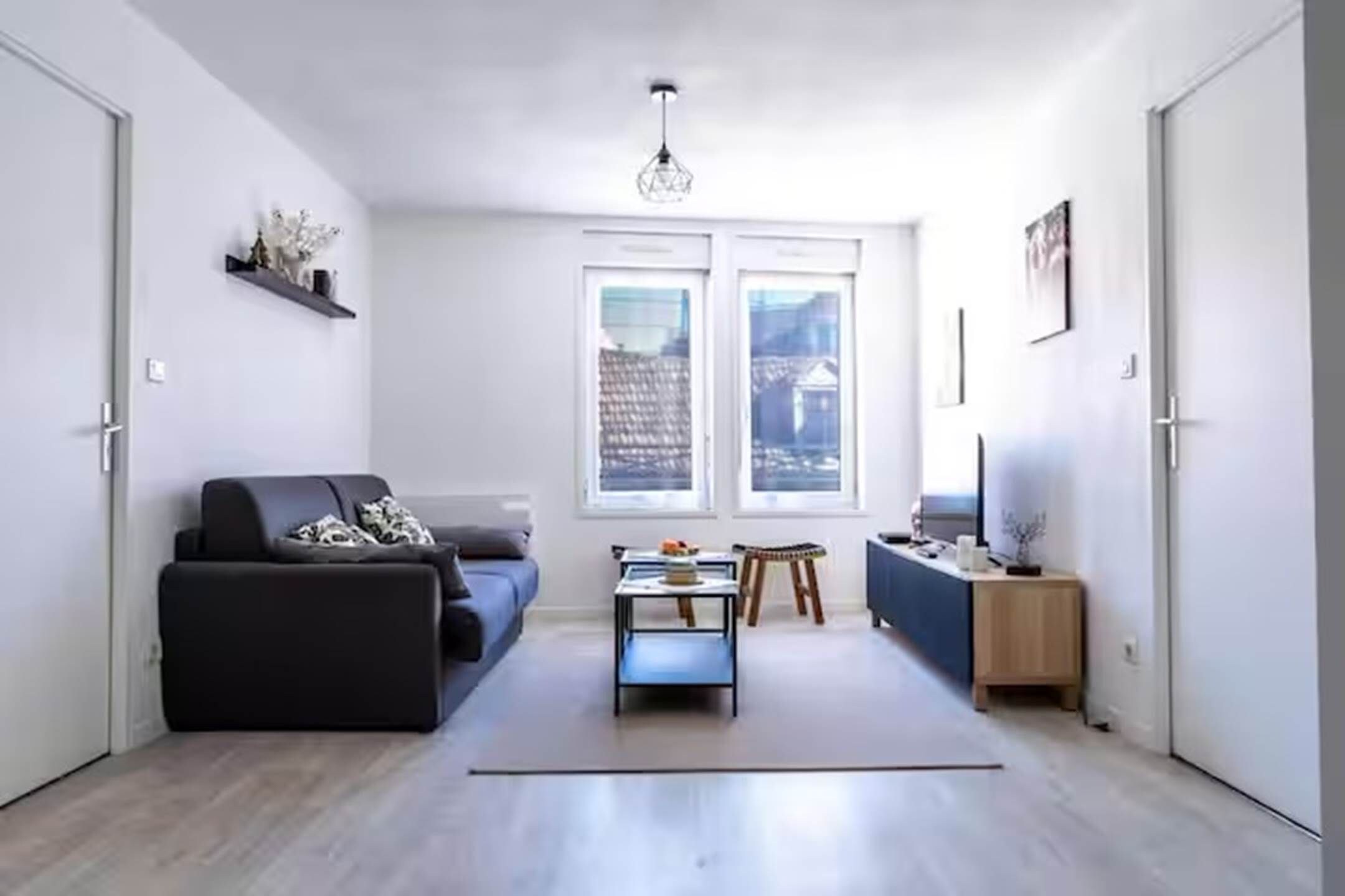 A modern living room with a sofa, a coffee table, and a TV stand.