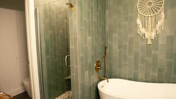 A bathroom with a freestanding bathtub, a glass shower enclosure, and a dreamcatcher decoration on the wall.
