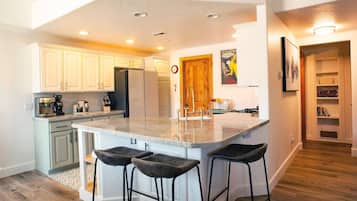 Una cocina moderna con una isla grande, taburetes de bar y una zona de comedor con puerta de madera.