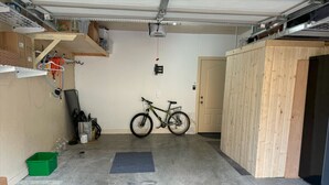 Un garage con una bicicletta, un contenitore portaoggetti verde e un tappetino sul pavimento.