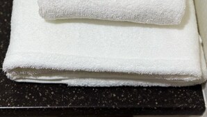 A neatly folded white towel stacked on a dark countertop. - Izumisano Home (Izumisano)