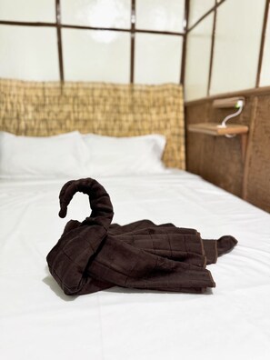 A neatly made bed with a brown towel folded on top.