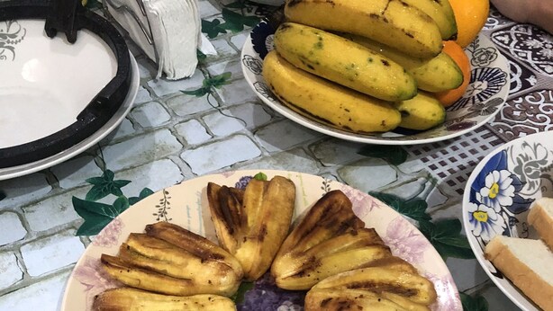 Un plato de plátanos fritos dispuestos en un círculo sobre una mesa con mantel floreado.