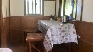 Una habitación de esquina con una mesa, un banco, un ventanal y un espejo.