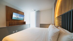 A hotel room with a large bed, a mounted TV, and a wooden headboard. - Jojo - 1 Bedroom Condo At Singular Joy (Playa del Carmen)