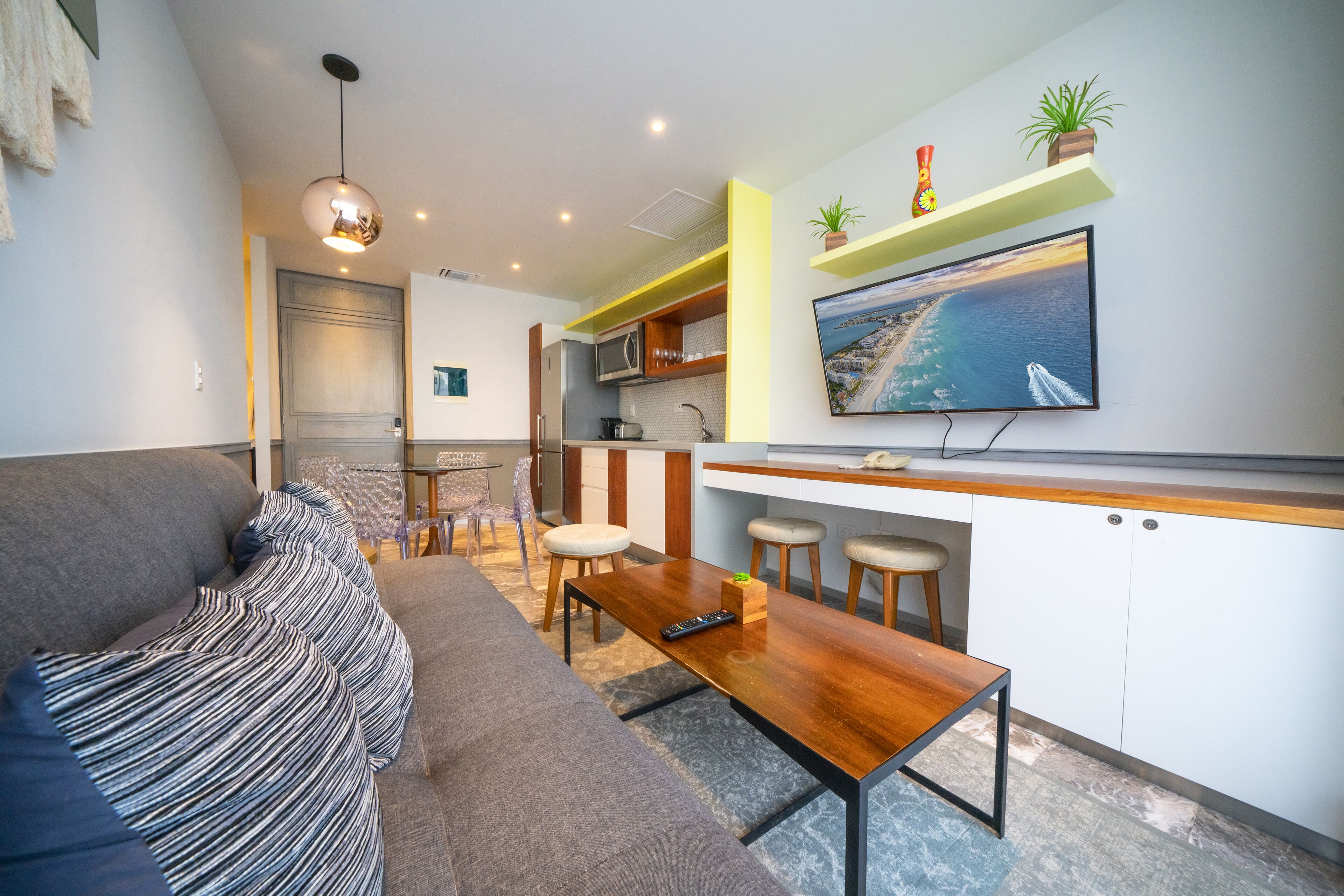 A modern living room with a sofa, a wooden coffee table, and a TV mounted on the wall.