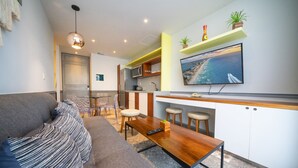 A modern living room with a sofa, a wooden coffee table, and a TV mounted on the wall. - Jojo - 1 Bedroom Condo At Singular Joy (Playa del Carmen)
