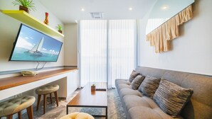 A modern living room with a flat-screen TV, a sofa, a coffee table, and a small bar area with stools. - Jojo - 1 Bedroom Condo At Singular Joy (Playa del Carmen)