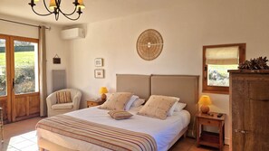 Relax in a spacious bedroom with a large bed, nightstand, dresser, and mirror, offering a peaceful view of the surrounding greenery.