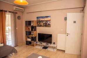 Een woonkamer met een televisie, planken, een deur en een schilderij.