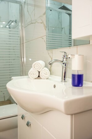 A bathroom with a white sink, a mirror, and a glass shower enclosure.