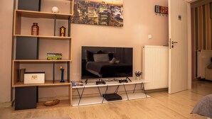Ein Wohnzimmer mit Fernseher, Regalen und Heizkörper.