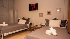 Ein Hotelzimmer mit zwei Betten, einem Holzschrank, einem kleinen Tisch mit Pflanze und einem Bild an der Wand.