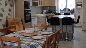 Une cuisine moderne avec des meubles en bois, un coin repas avec une nappe à carreaux et un bar avec des tabourets.