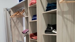 Un dressing avec de nombreuses étagères en bois, une tringle pour suspendre les vêtements et des tiroirs.