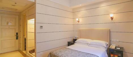 Una habitación de hotel con cama, mesitas de noche, una lámpara de pared y una puerta.
