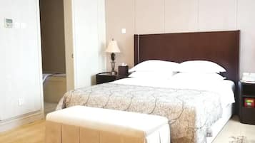 A hotel room with a large bed, bedside tables, a bench, and a wardrobe.
