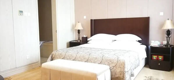 A hotel room with a large bed, bedside tables, a bench, and a wardrobe. - Xing Lin Wan Hotel (Xiamen)
