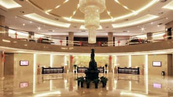 A spacious lobby with a central fountain, multiple seating areas, and a high ceiling with a large chandelier.