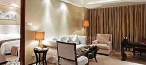 A hotel room with a bed, two armchairs, a sofa, a coffee table, and a lamp. - Xing Lin Wan Hotel (Xiamen)