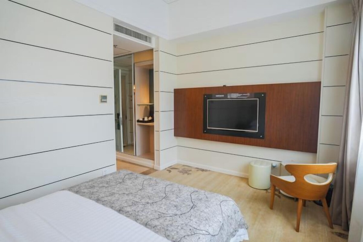 A hotel room with a bed, a TV mounted on the wall, a chair, and a small table.