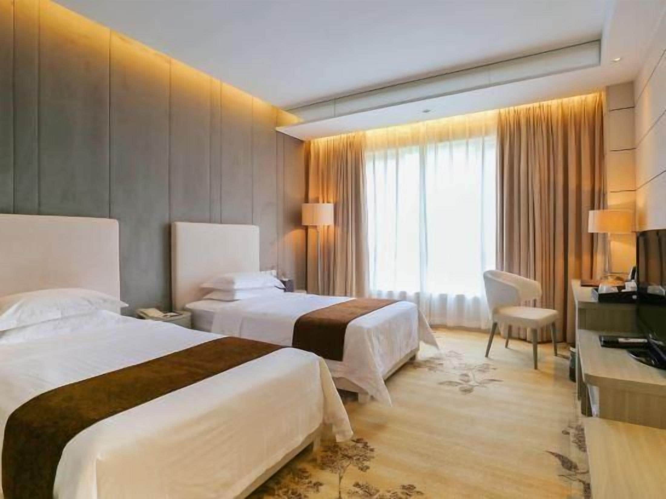 Una habitación de hotel con dos camas, un escritorio, una silla y una televisión.