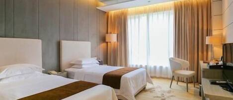 Una habitación de hotel con dos camas, un escritorio, una silla y una televisión.