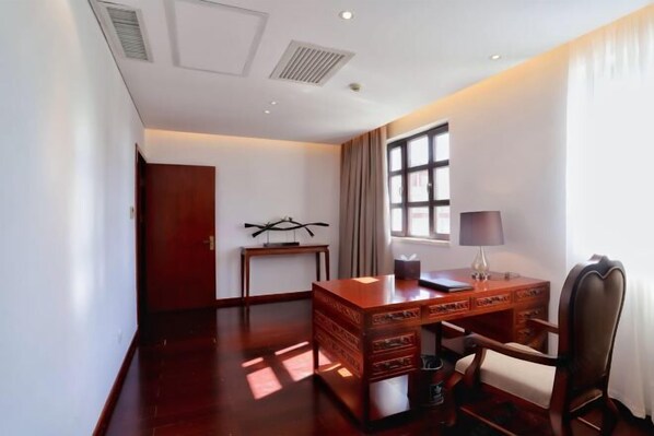 A spacious room with a wooden desk, a chair, a lamp, and a window with curtains. - Xing Lin Wan Hotel (Xiamen)