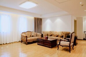 A living room with a sofa, armchair, and coffee table. - Xing Lin Wan Hotel (Xiamen)