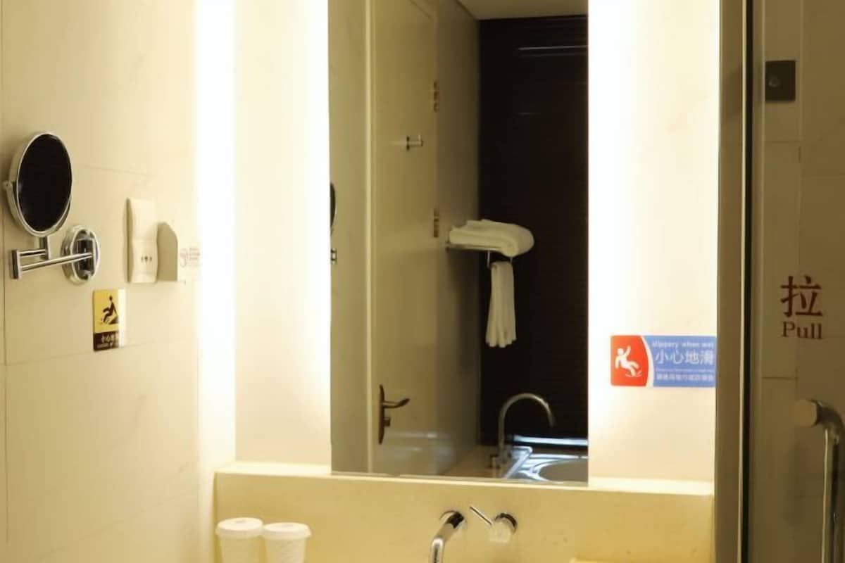 A bathroom with a mirror, a towel rack, a toilet paper dispenser, and a sign indicating a pull handle.