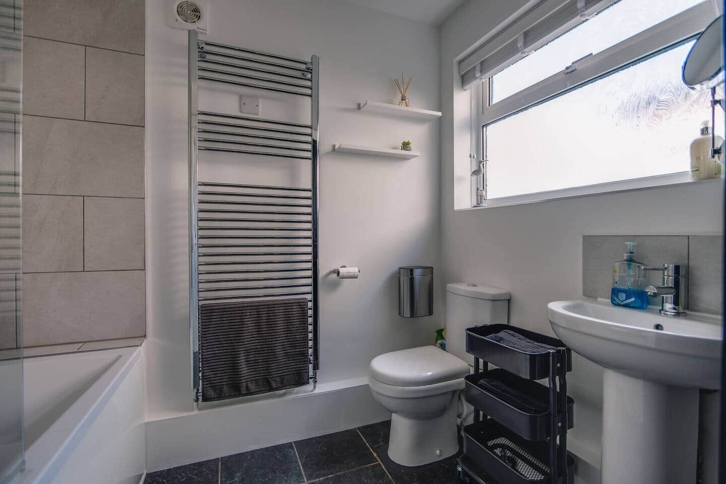 Une salle de bain équipée d’un WC, d’un lavabo, d’une fenêtre et d’un porte-serviettes.