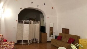 Una stanza con un divano, una televisione, uno specchio e un pannello decorativo.