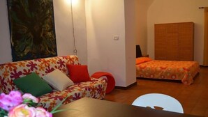 Una stanza accogliente con un divano floreale, un letto con copriletto arancione e un armadio in legno.