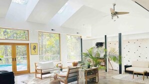Un salon spacieux avec un plafond haut, de grandes fenêtres et un ventilateur de plafond.